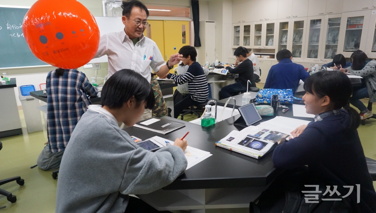 IB로 교육하는 일본 삿포로 가이세이 중등교육학교의 과학 교사가 중3 수업에서 지구 모양의 큰 풍선을 들고 학생 질문에 답변해 주고 있다.