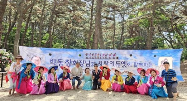 ‘맨발 아미사 힐링센터’에 걸려 있는 박동창 회장 특강안내 현수막 앞에서 아미사 요들합창단이 기념 촬영하고 있다.
