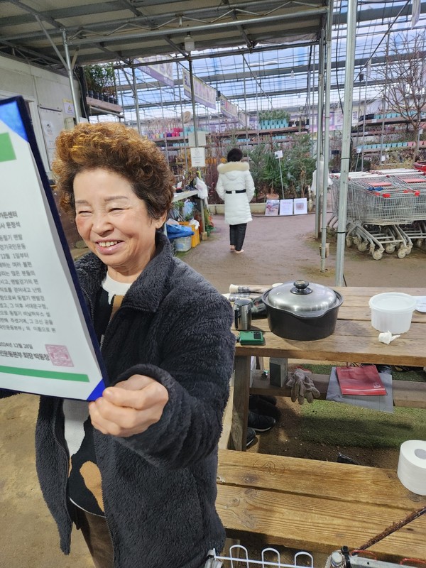 우림원예가든센터 문정석 대표이사의 장모 정현자 씨가 감사장을 들고 활짝 웃고 있다.