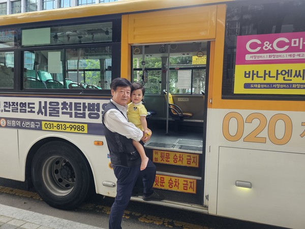 버스를 배경으로 외손주를 안고 있는 김민수 씨.